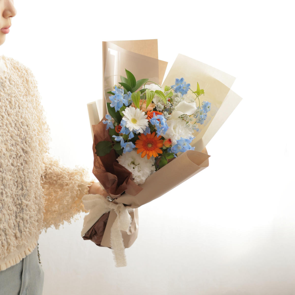 花束を手に ガーベラが入ったオレンジが引き立つ爽やか小花の花束｜フラワーギフト